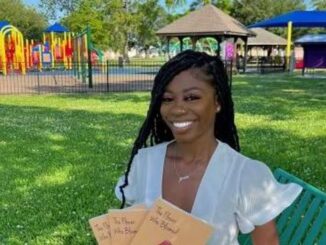 Jada White poses with her first published poetry book, “The Flower Who Bloomed.” (Jada White)