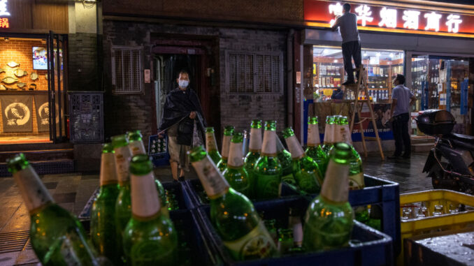 A man carries empty beer bottles as he collects them from a restaurant in a hutong neighborhood on September 8, 2021 in Beijing, China. (Photo by Kevin Frayer/Getty Images)
