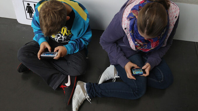 Children play video games on smartphones while attending a public event on September 22, 2012 in Ruesselsheim, Germany. (Photo by Sean Gallup/Getty Images)