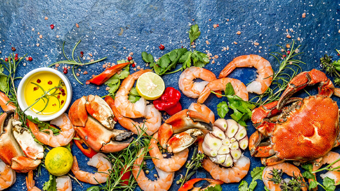 Baner. Fresh raw seafood - shrimps and crabs with herbs and spices on blue background. Copy space